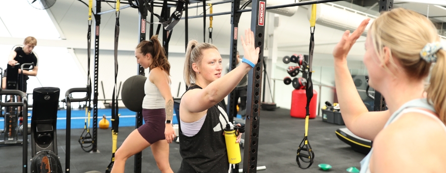 Two women high-fiving one another in a gym.