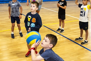 Young child about to shoot a volleyball while team crowds around