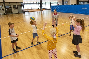 Young children practise passing the volleyball to each other