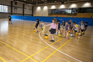 Group of young children learn to guide a futsal ball while running
