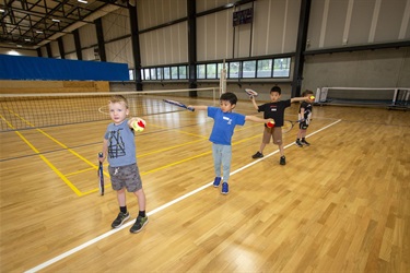 Youngest children practise hitting a tennis ball with their racquet