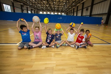 A group of children show the range of sports they enjoy in the school holiday programs