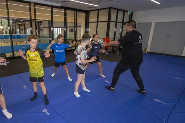 A class of older kids learn the palm heel strike in karate