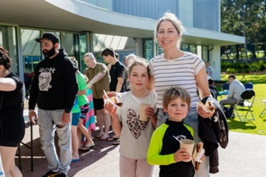A woman and two children with sausages in bread.