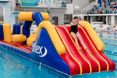 A child going down an inflatable slide in the pool