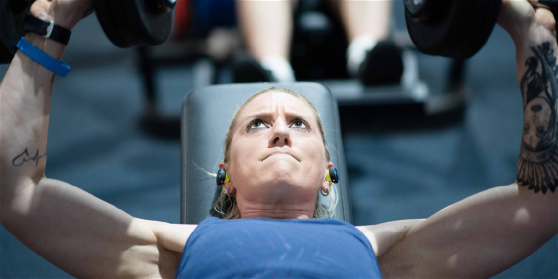 Person lifting weights in the gym with determined face