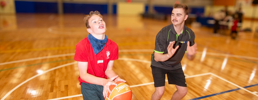 Coach and youth on a basketball court practising how to shoot