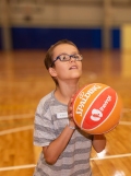 Child holding a basketball is looking up ready to take a shot