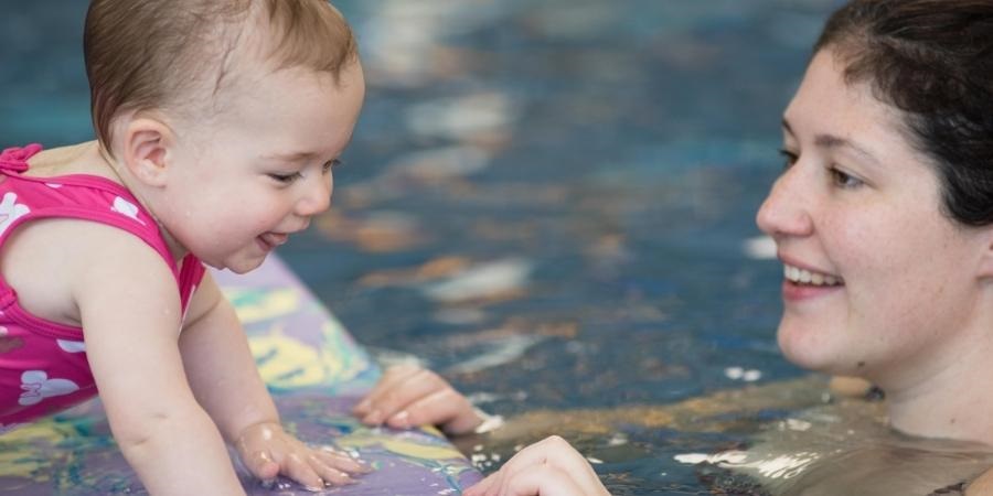 Adult swimming with a child in a swimming pool