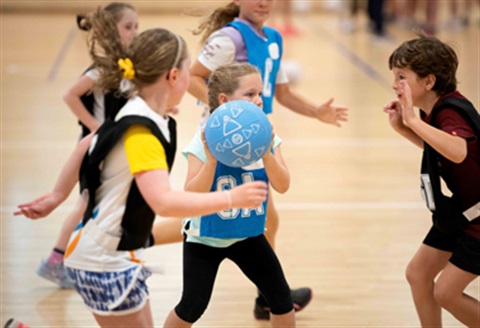 Ball in mid air between youths as they play netball game during Maroondah Nets School Holiday program