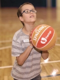 Child holding a basketball is looking up ready to take a shot